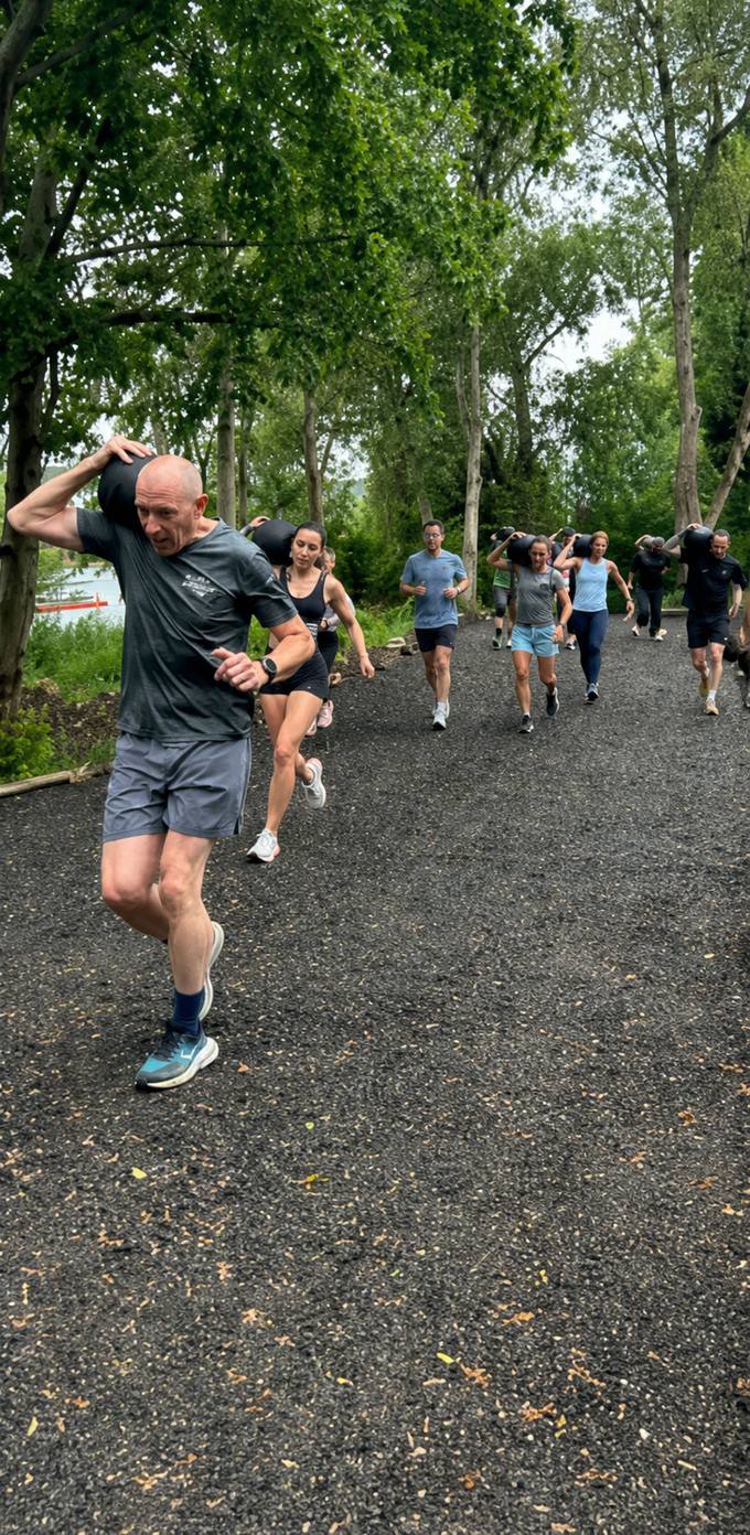 Group sandbag-carry run along the lakeside trail