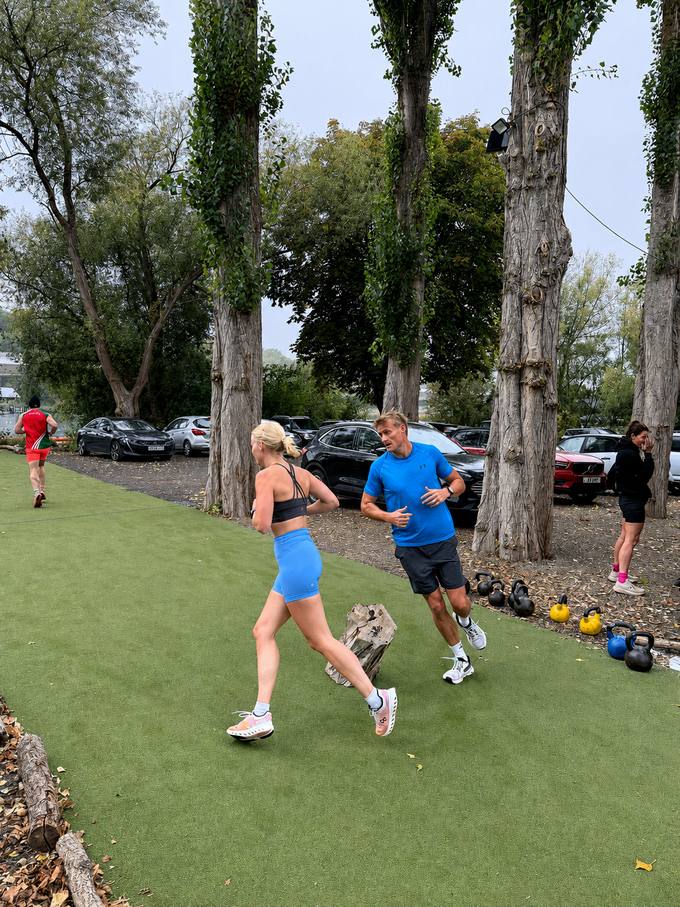 Members running on the turf with a coach during an outdoor BODY HEALTH FITNESS session